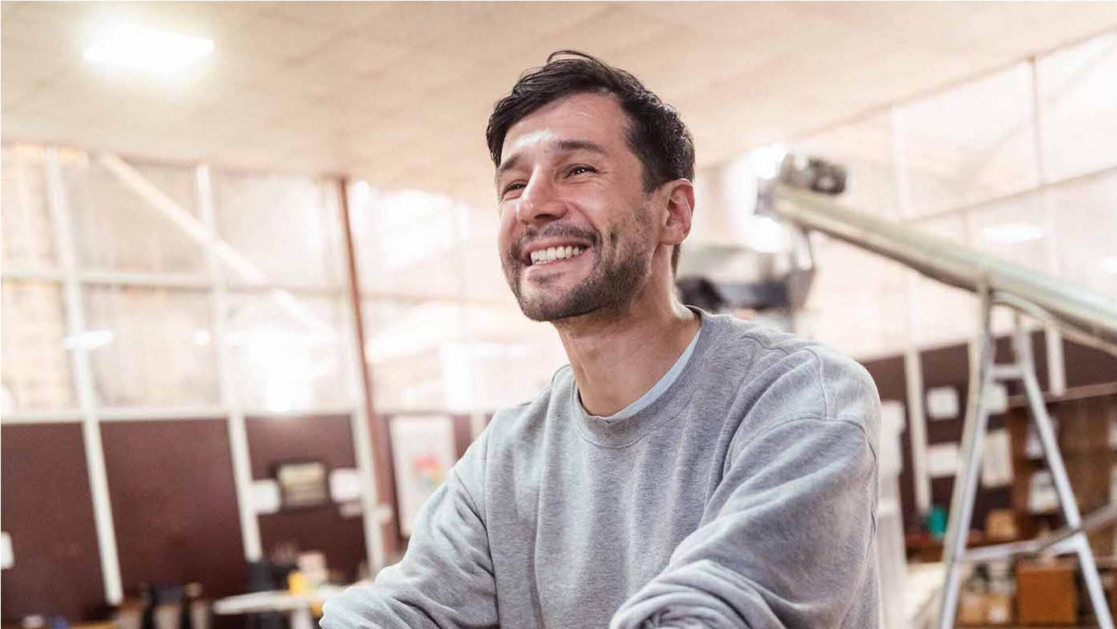 Lächelnder Mann in einer Kaffeerösterei – Gründer bei der Arbeit in entspannter Atmosphäre
