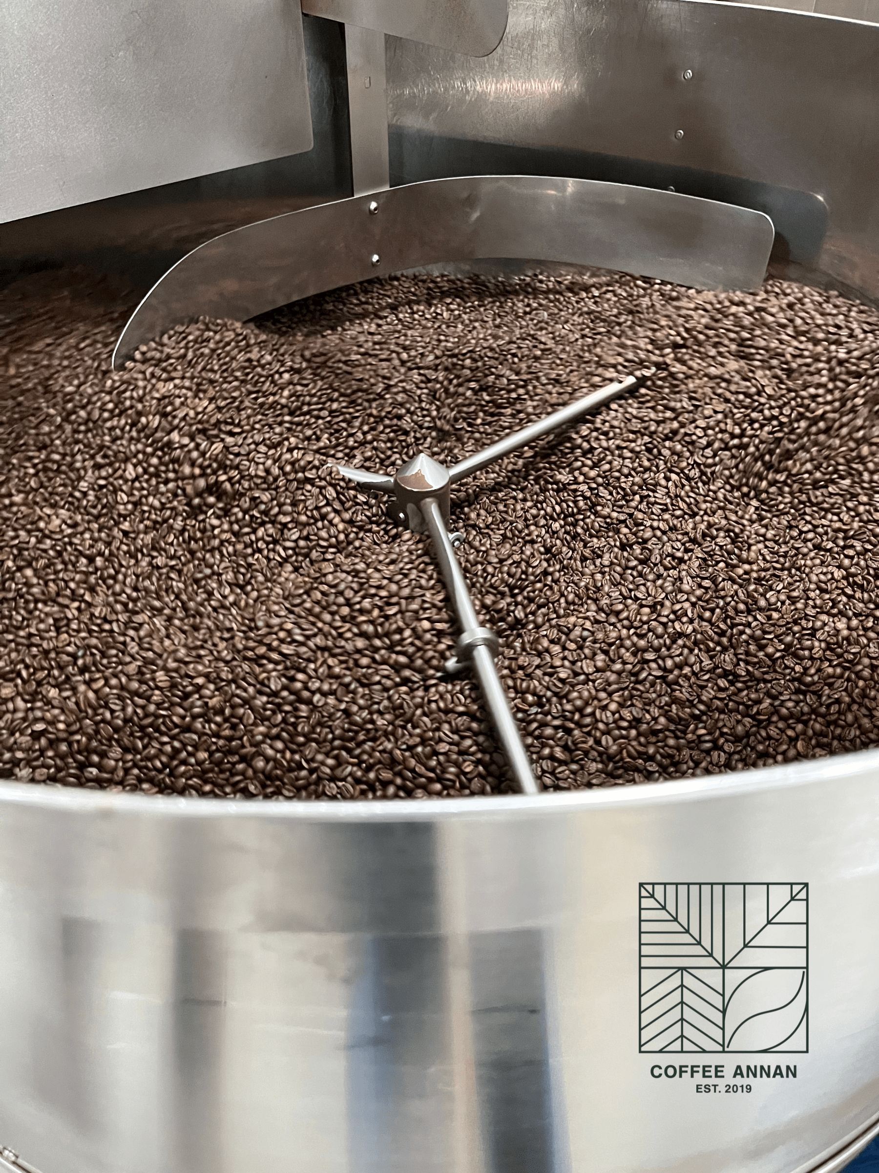 Kaffeebohnen in einer industriellen Trommelröstmaschine mit Rührarm in Nahaufnahme